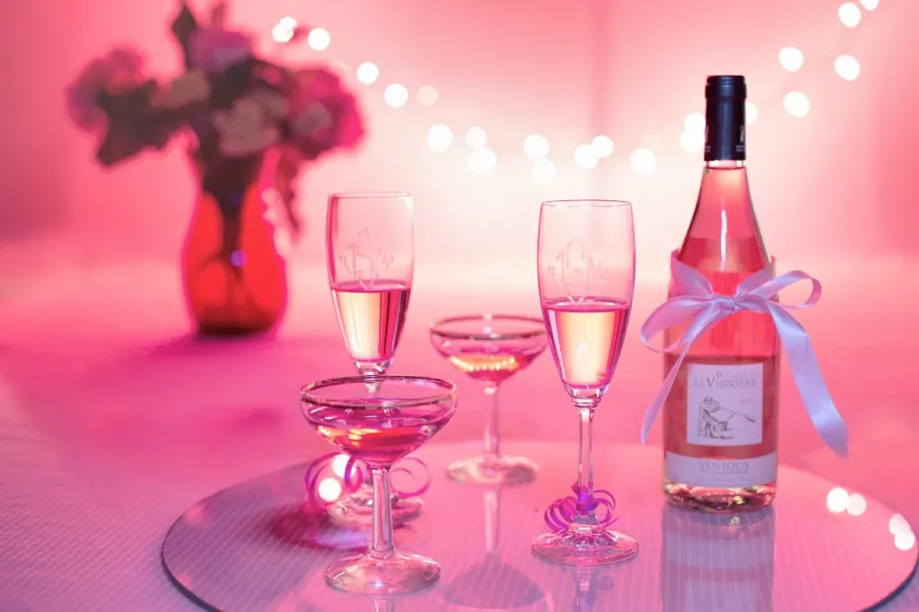 Elegancka butelka alkoholu z ozdobną winietką na weselnym stole w ciepłym świetle zachodzącego słońca.
